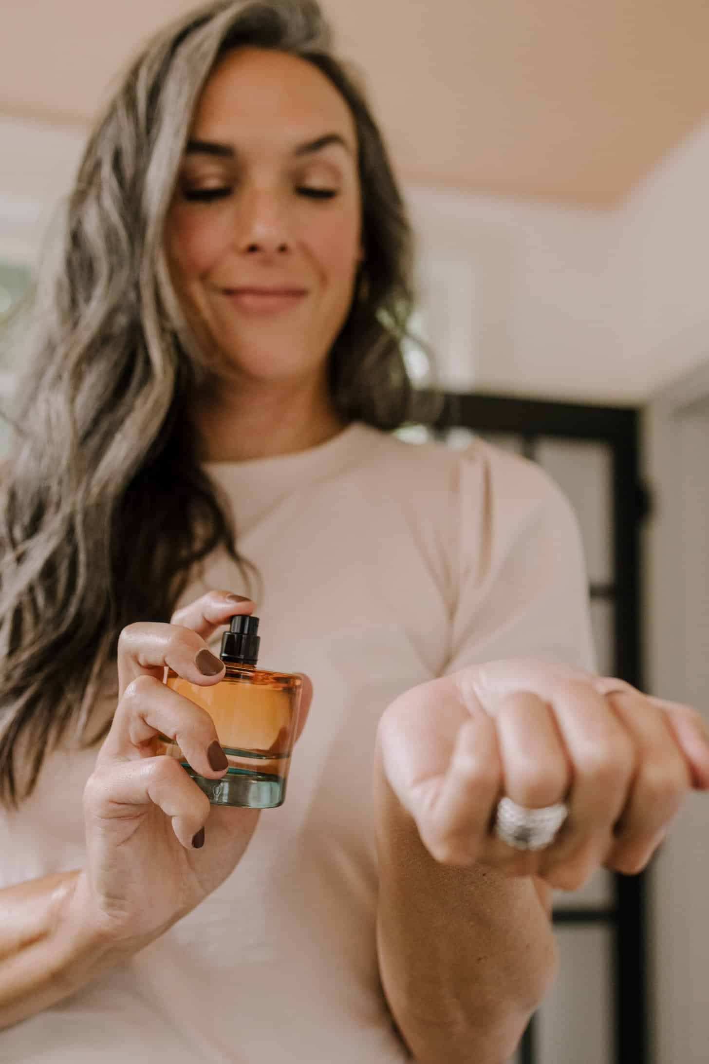 a woman sprays her wrist with a clean perfume