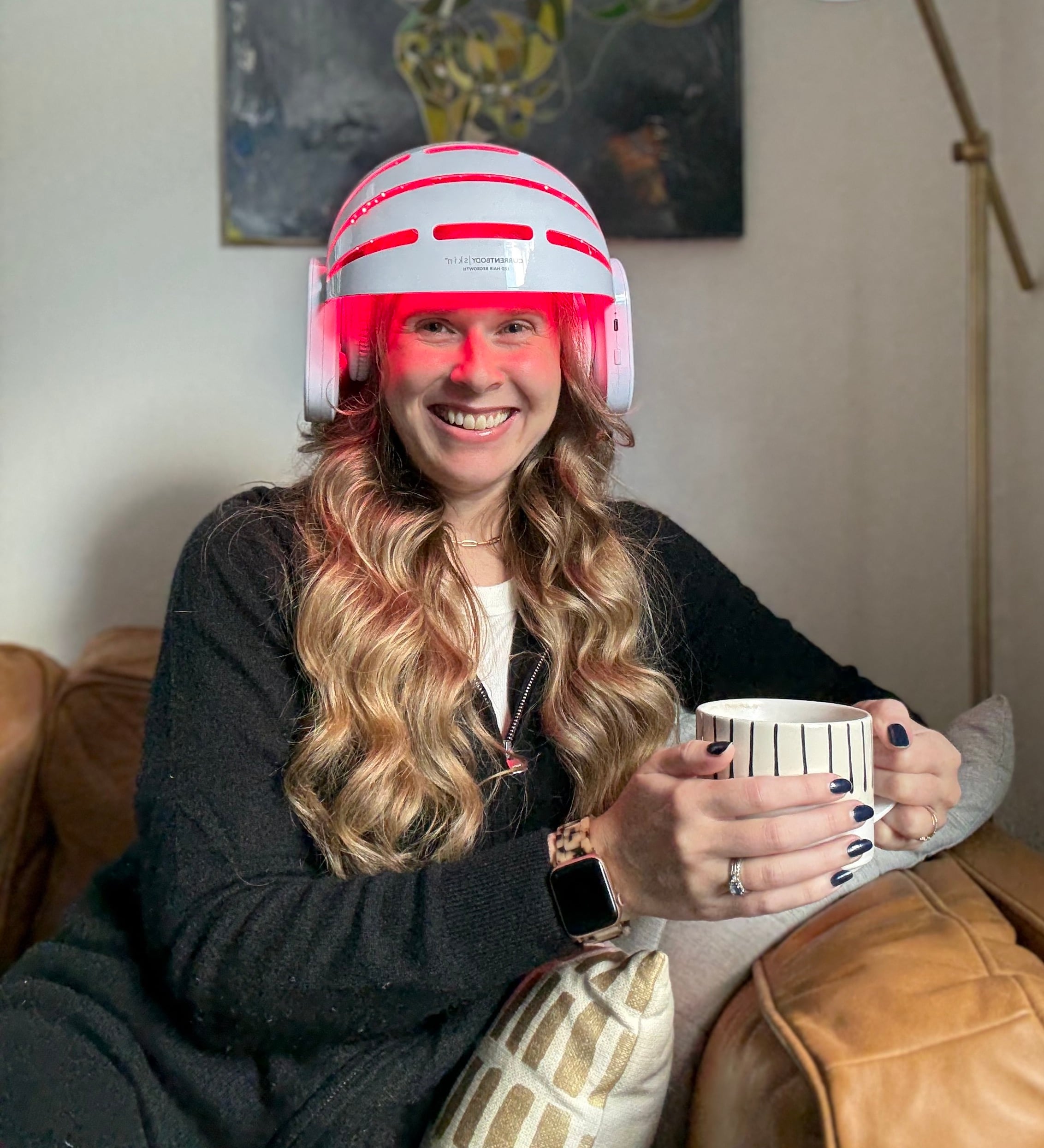A woman with long blonde hair wearing a red light therapy helmet.